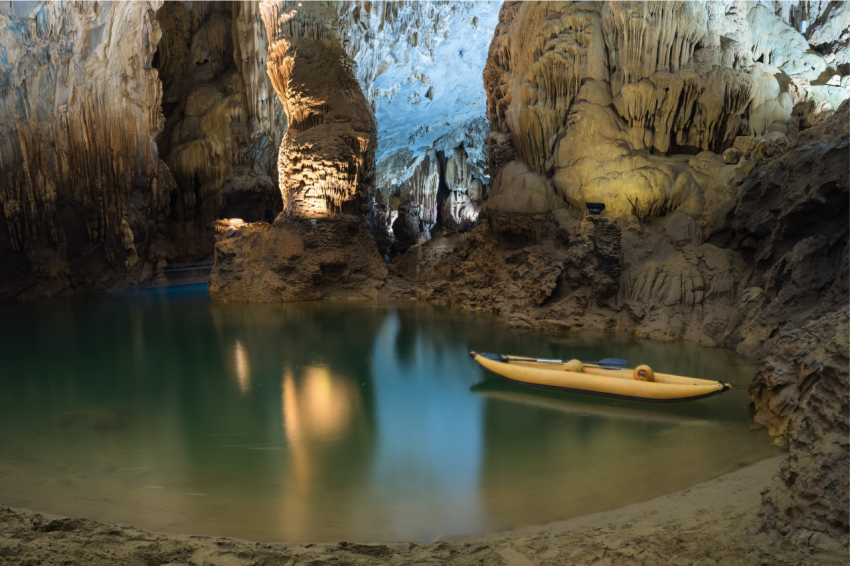 River and rock cliff, and rowing tourist boat inside of Phong Nha Cave in Phong Nha Ke Bang National Park, a UNESCO World Heritage Site in Quang Binh Province, Vietnam